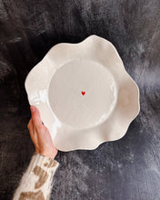 Carica l'immagine nel visualizzatore di Gallery, A hand holding a ceramic bowl with a tiny heart in the middle on a black background