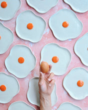 Carica l'immagine nel visualizzatore di Gallery, Egg Spoon Rest made of stoneware with an egg being held over decorative plates in a fun kitchen setup.