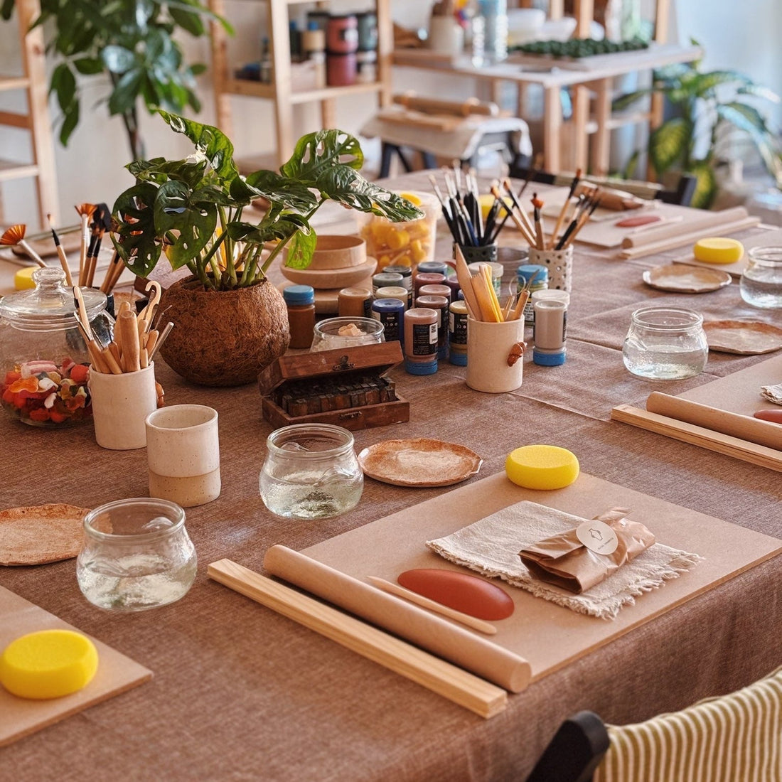 A table set up for a pottery workshop featuring colours and tools
