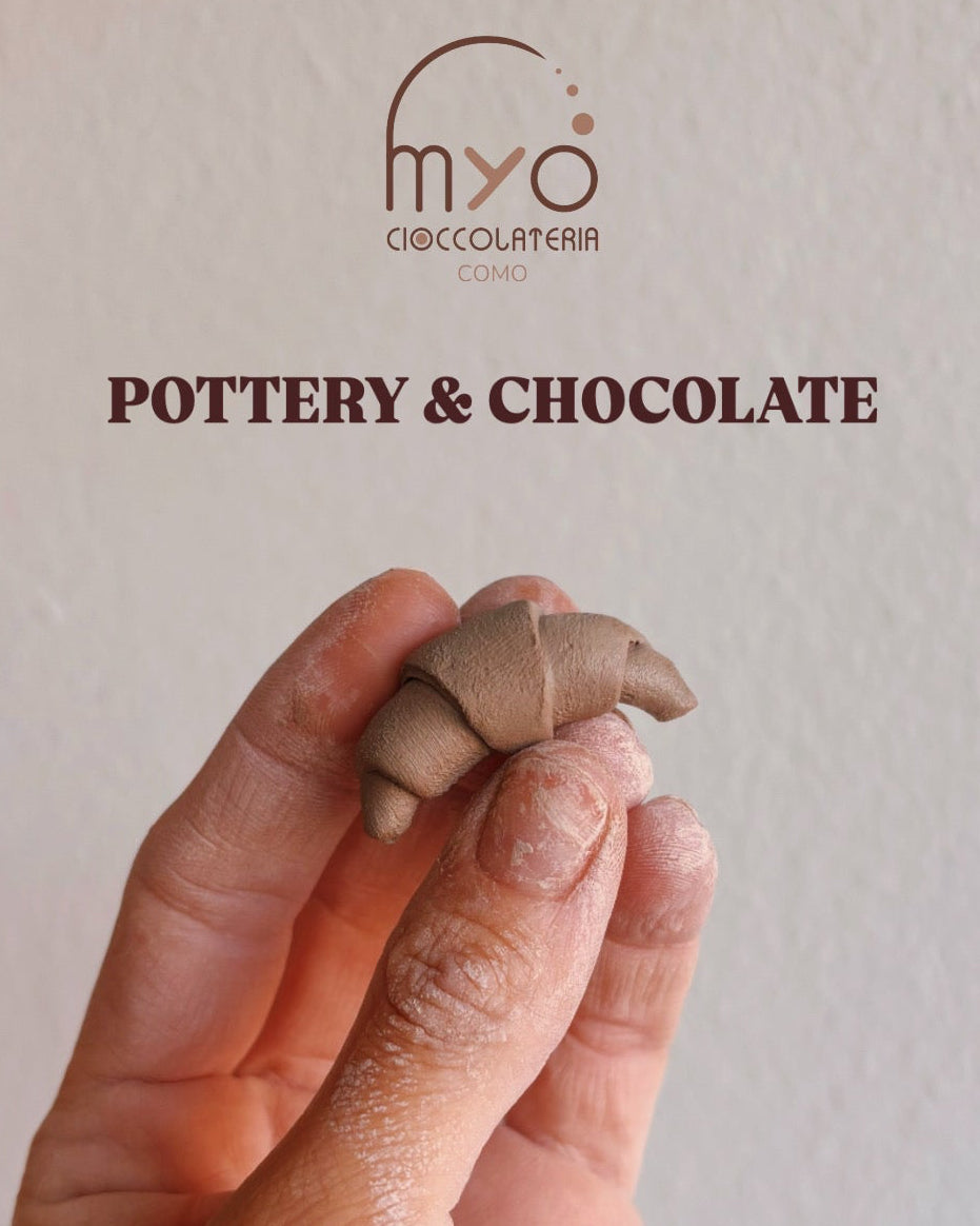 A hand holds a small clay croissant above a textured off-white background with the logo and text 'POTTERY & CHOCOLATE' 