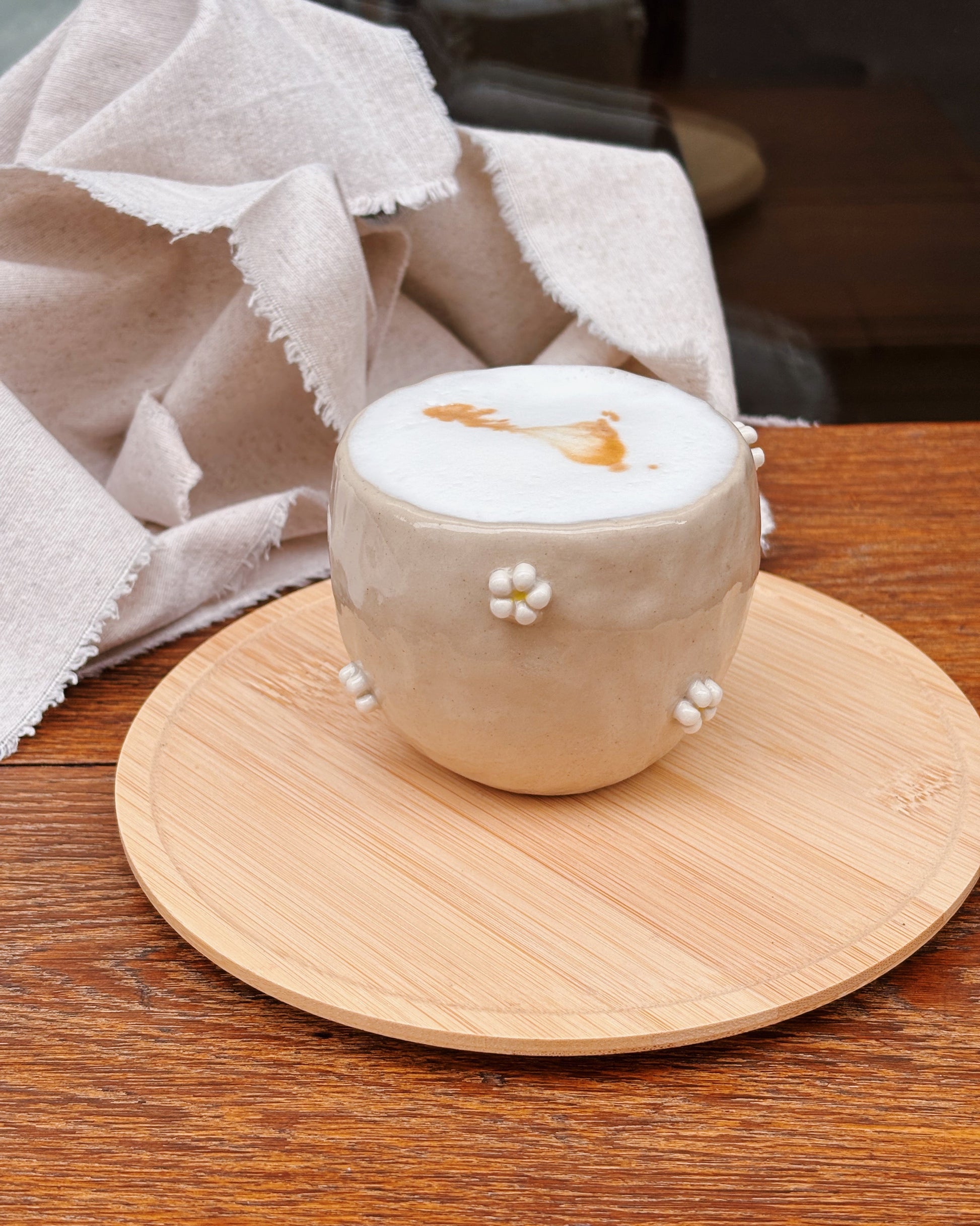 Cup of coffee with decorative elements on a wooden coaster