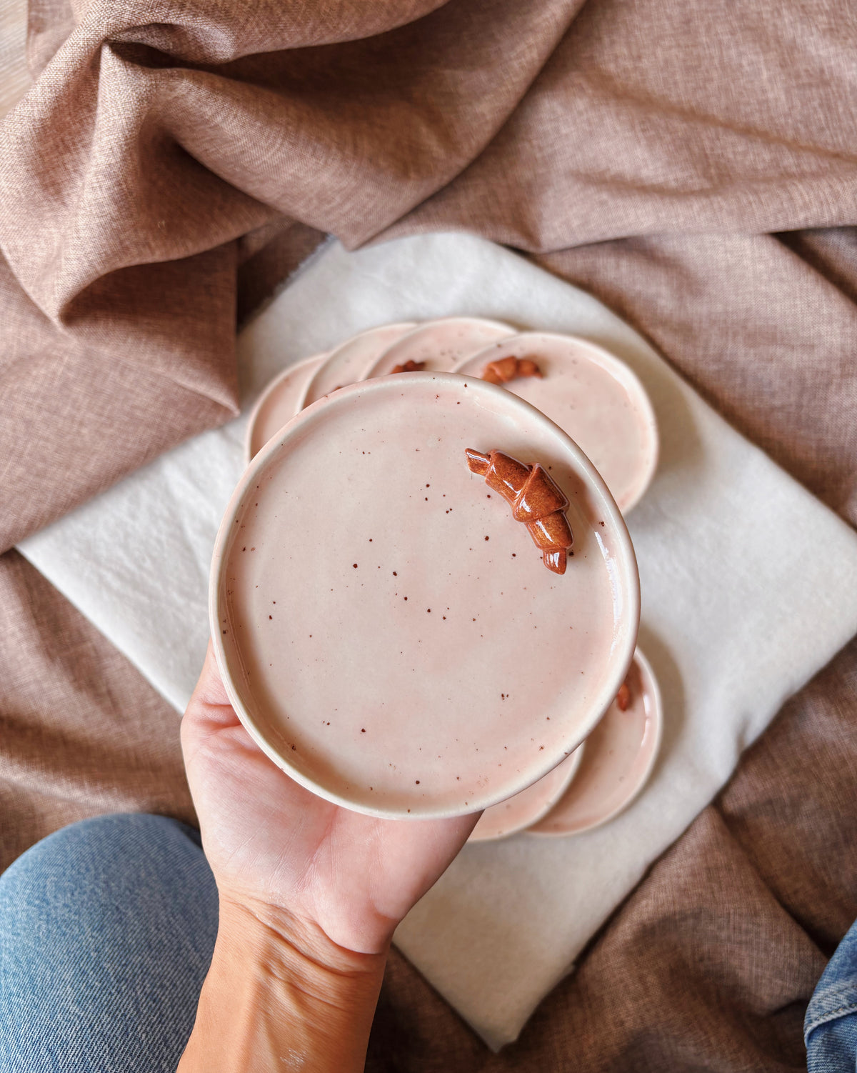 A handmade ceramic pink plate with a small croissant on top