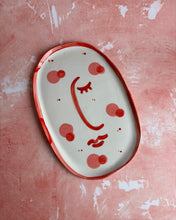 Carica l'immagine nel visualizzatore di Gallery, Decorative plate with a face design on a pink surface
