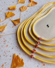 Load image into Gallery viewer, Set of ceramic plates with yellow rims on a textured surface with autumn leaves.
