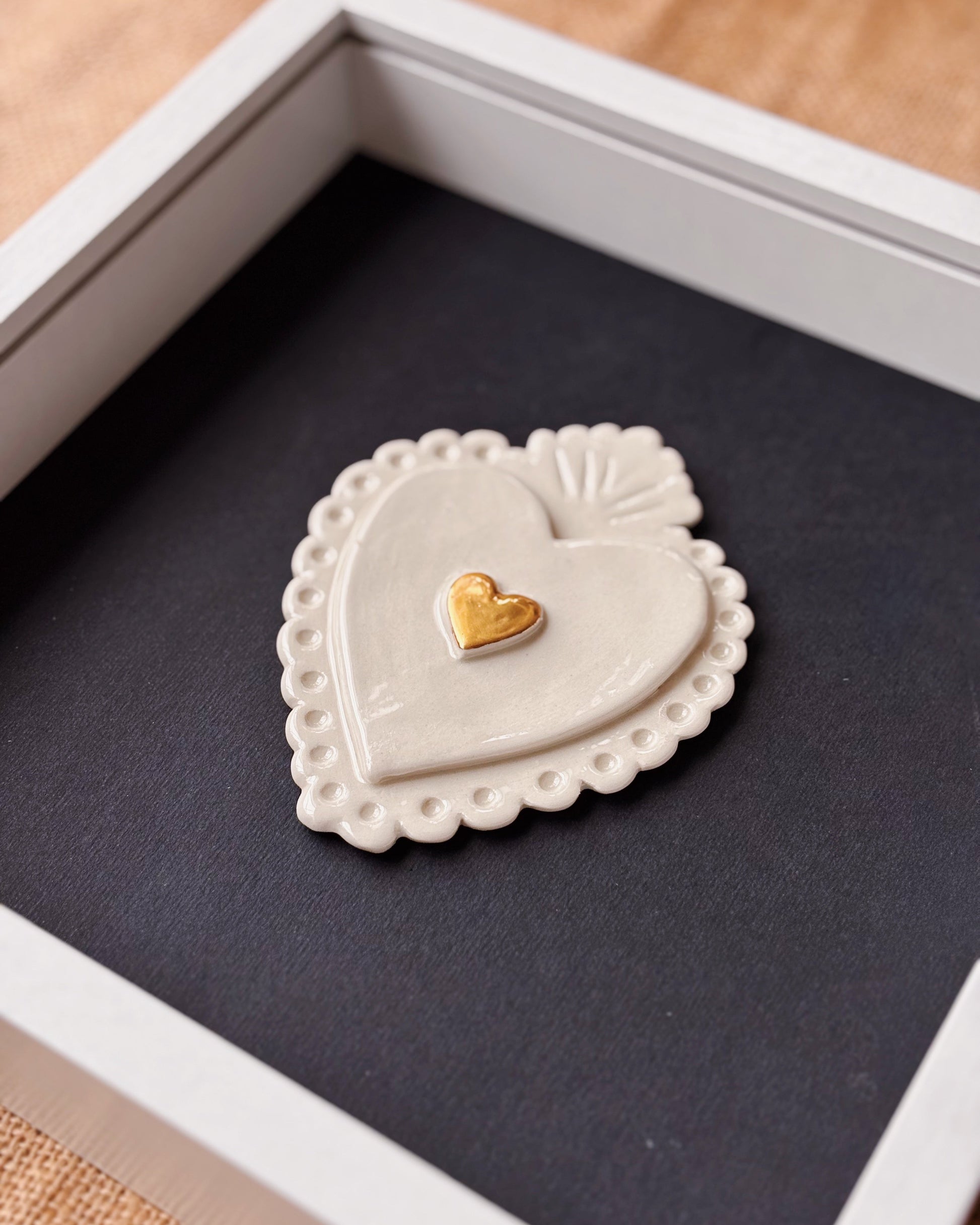 Heart-shaped ceramic object with a gold heart on a dark surface
