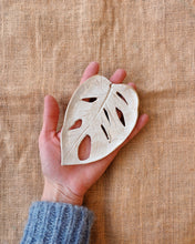 Load image into Gallery viewer, Hand holding a ceramic leaf-shaped ornament against a textured beige background
