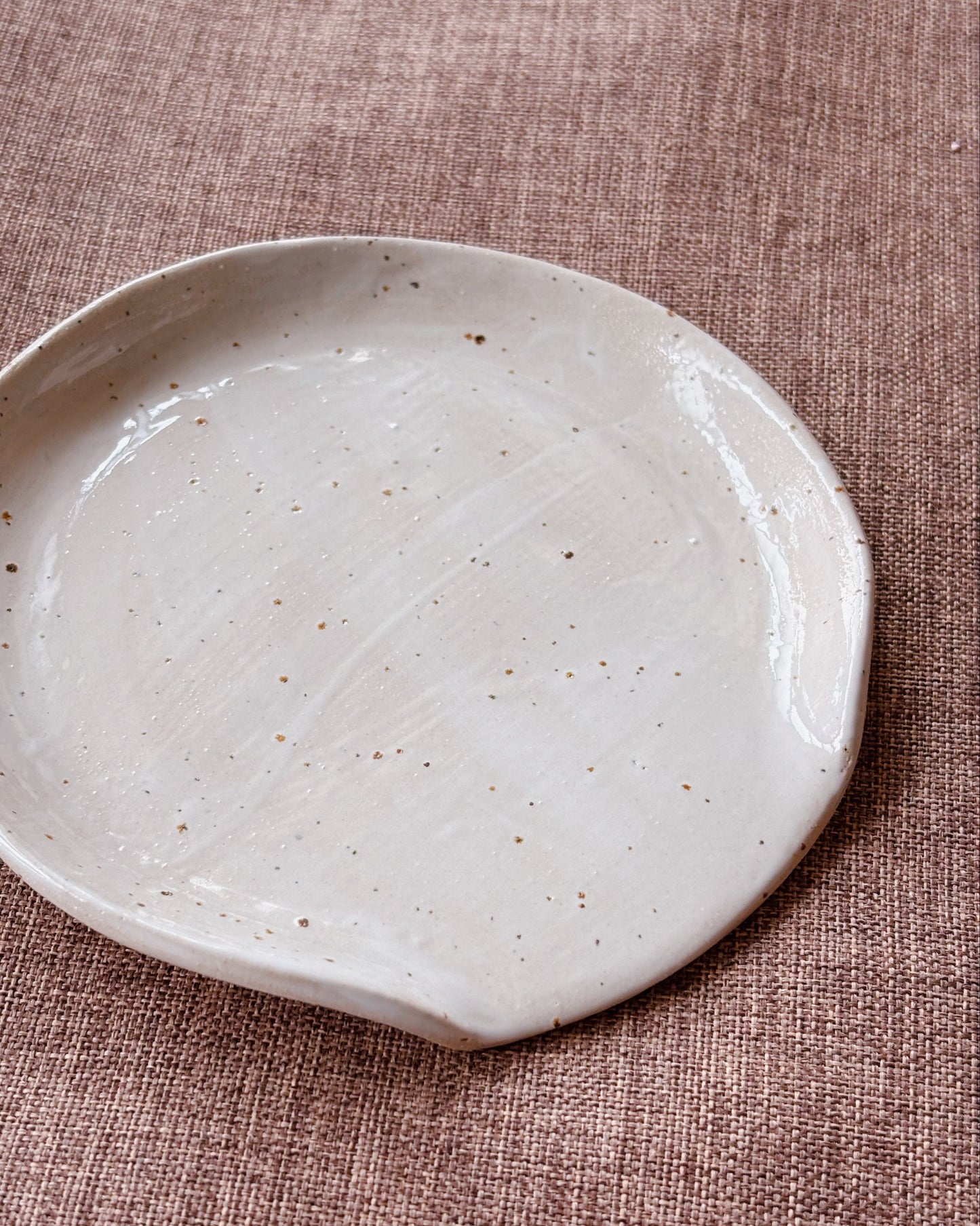 White ceramic plate with speckled texture on a brown textured surface