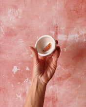 Load image into Gallery viewer, Hand holding a handmade stoneware croissant espresso mug against a pink background.
