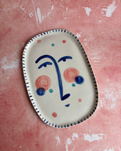 Carica l'immagine nel visualizzatore di Gallery, Ceramic plate with face design on a pink textured background
