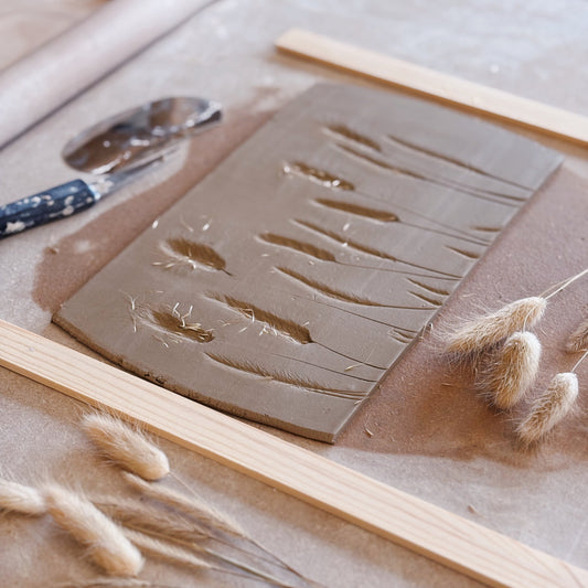 Clay slab with textured patterns and wooden tools on a table