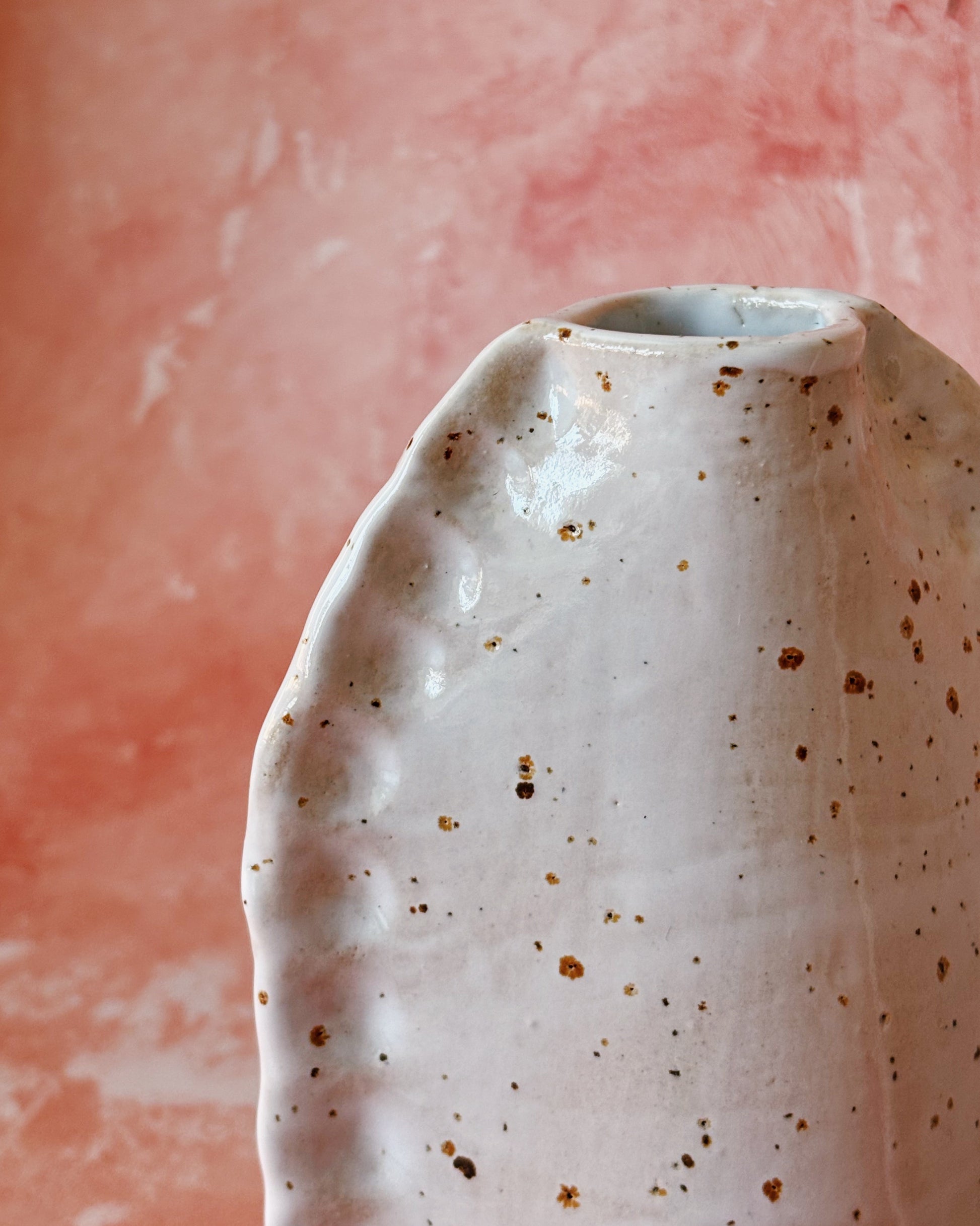 Speckled ceramic vase on a pink background