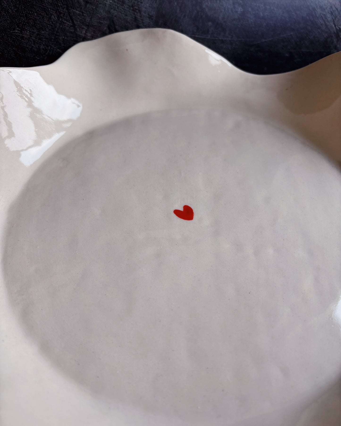 A ceramic bowl with a tiny heart in the middle on a black background