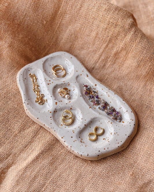 Jewelry tray with gold rings on a beige fabric background