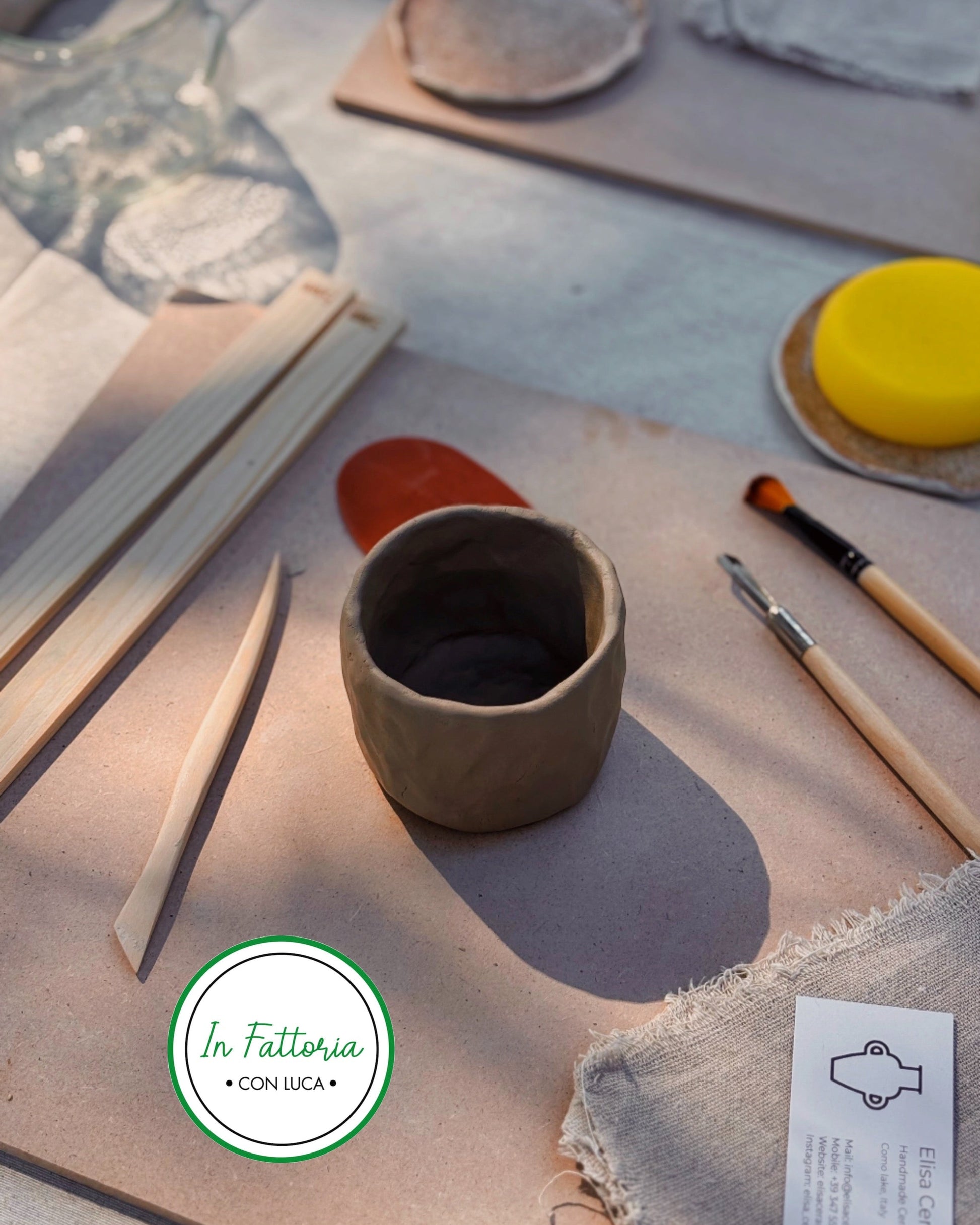 Ceramic cup on a table with pottery tools and raw clay