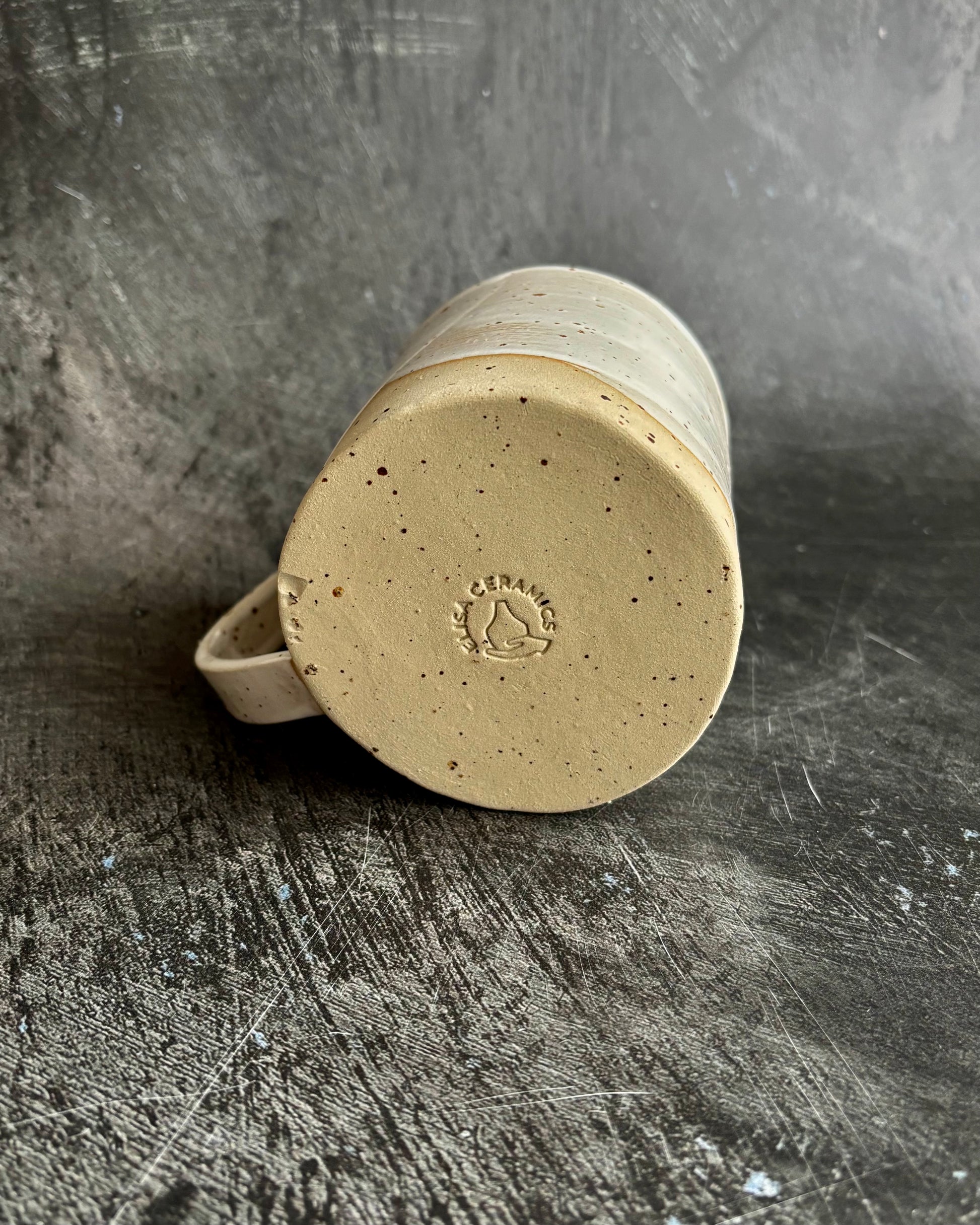 Bottom of a mug branded with a special speckled clay on a black background