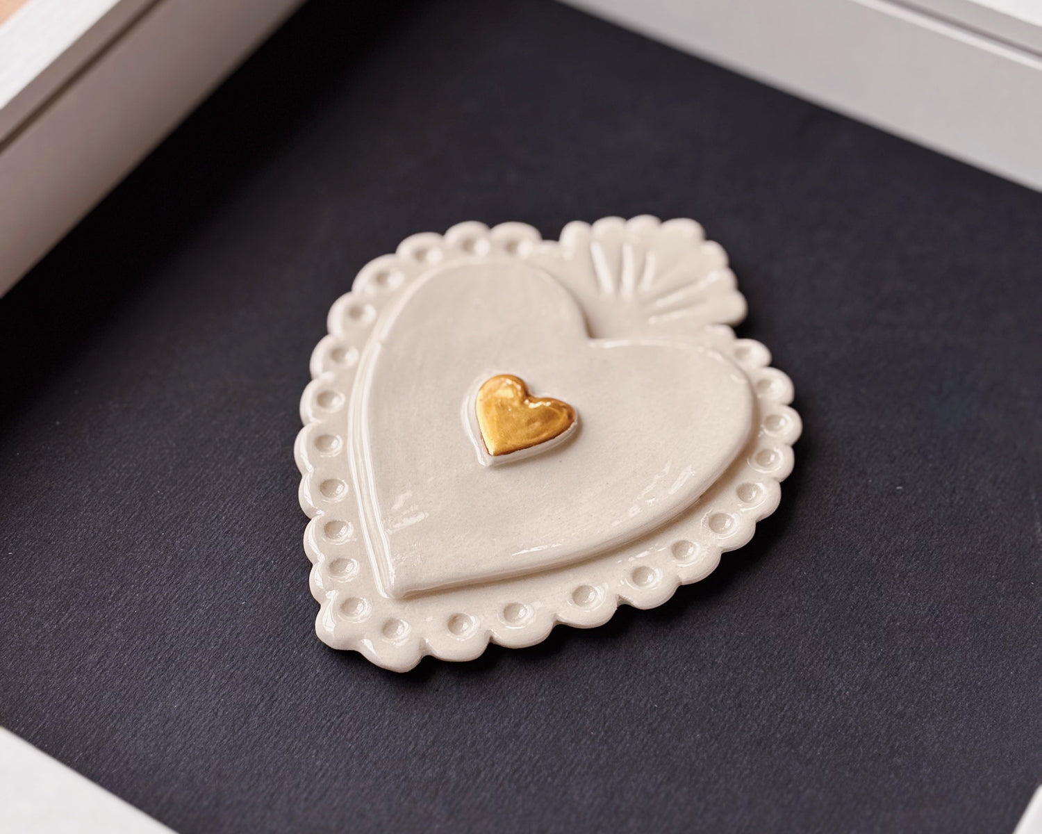 Heart-shaped ceramic piece with a gold heart inset on a dark surface