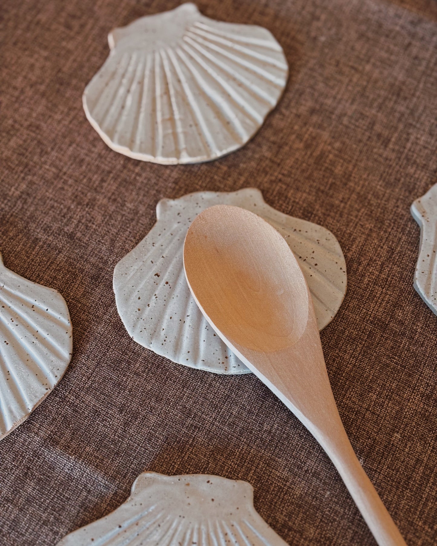 A spoon resting on a spoon rest made of ceramic with the shape of a shell