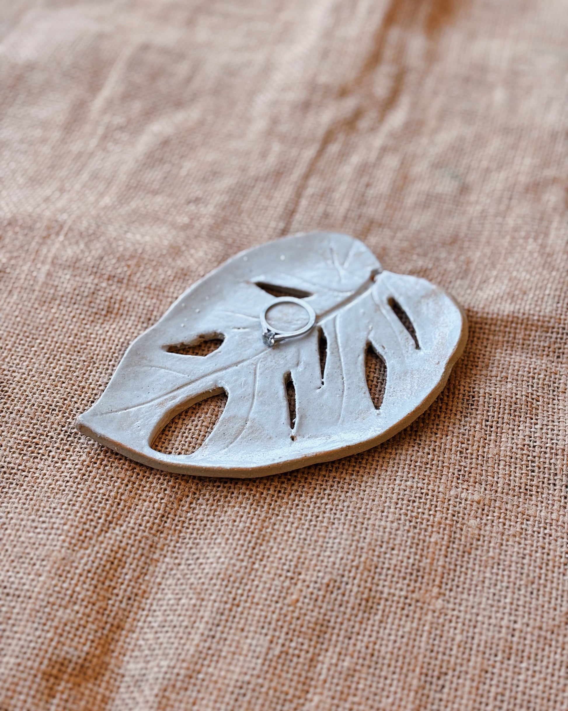 Ceramic leaf-shaped dish on a textured fabric surface