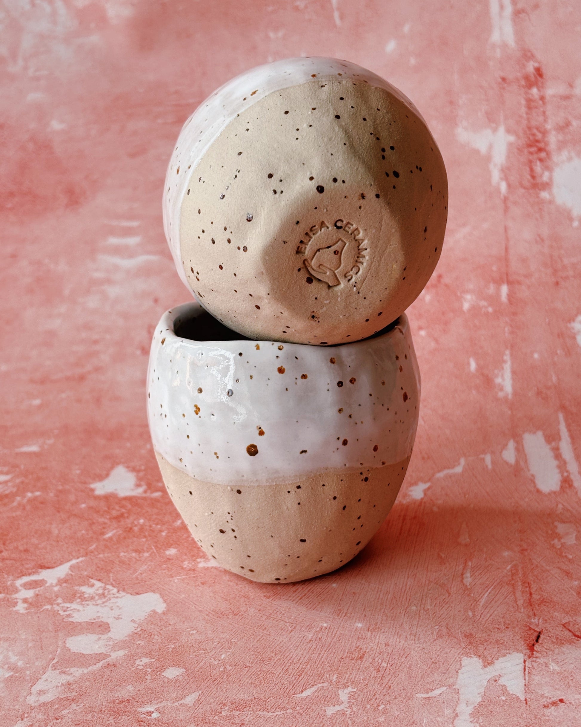 Two ceramic bowls stacked on a pink textured background