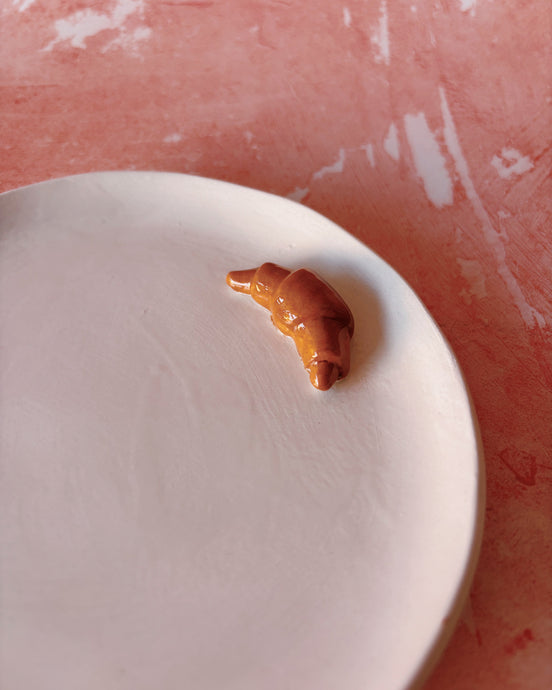 Croissant Small Ceramic Plate featuring a croissant on a handmade stoneware surface.