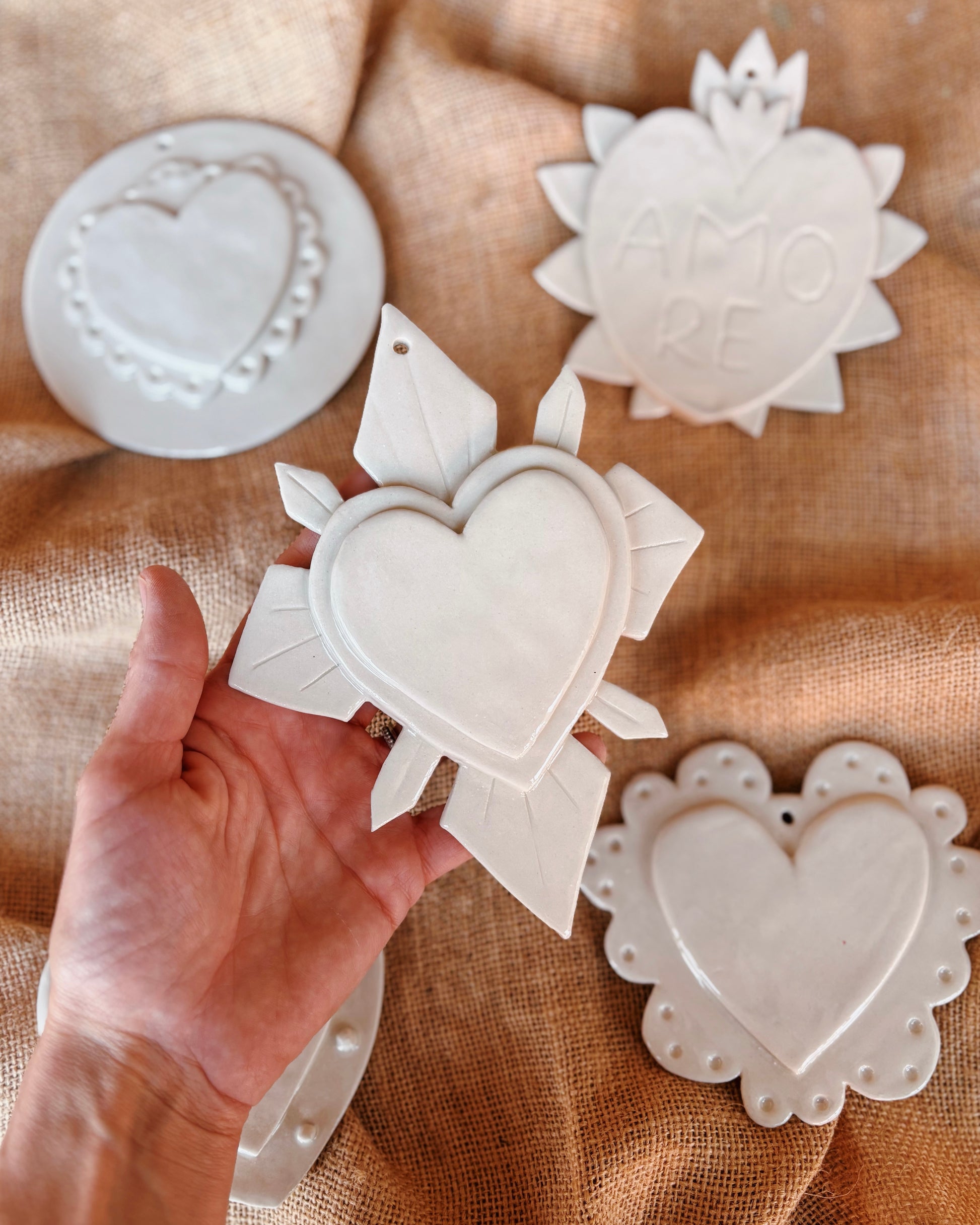 A hand holding a white sacred heart made of ceramic