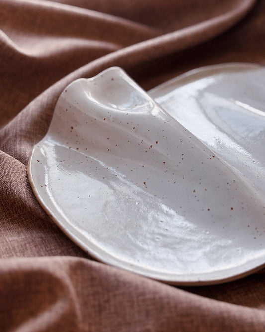 Speckled ceramic dish on a textured brown fabric background