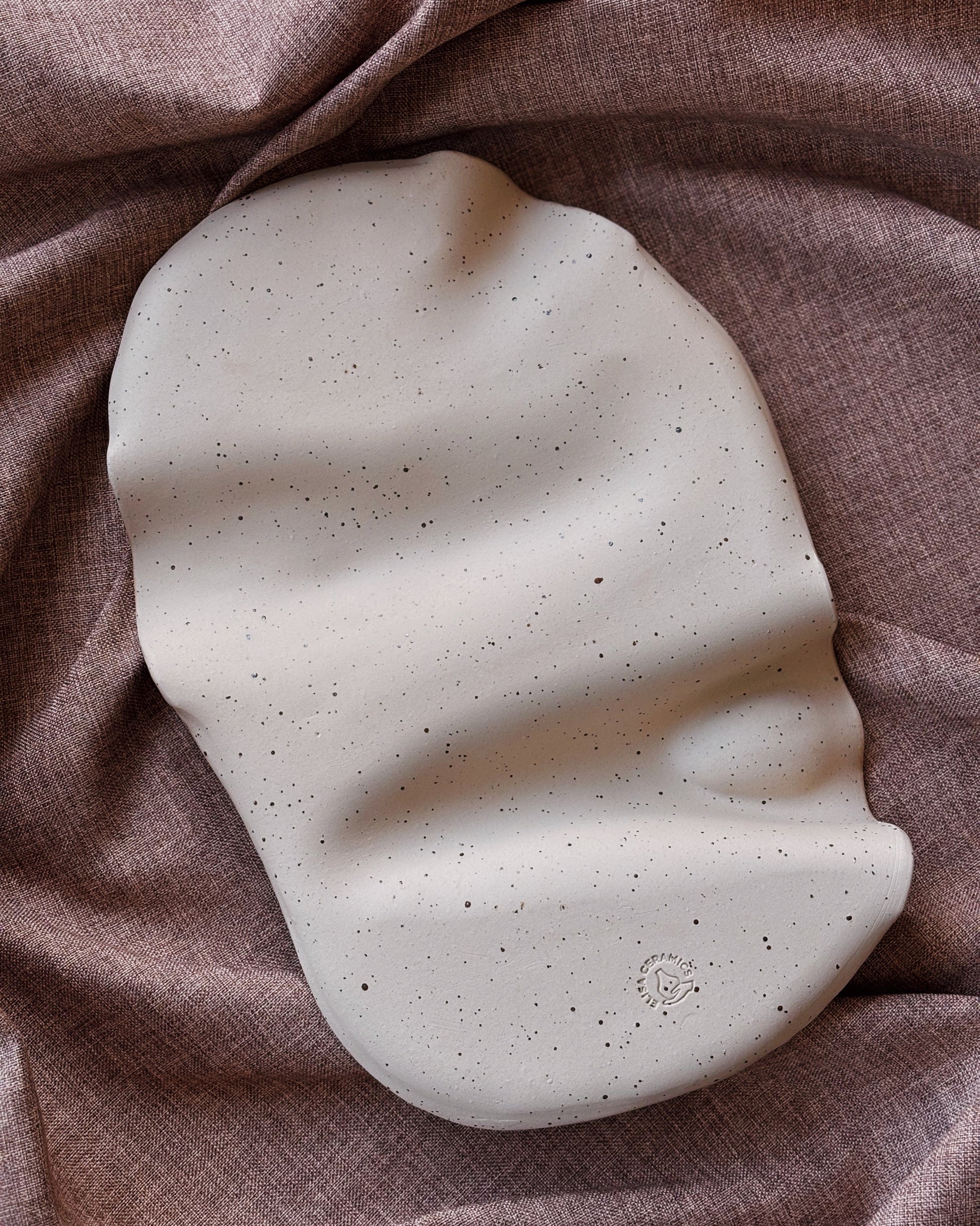 Speckled ceramic plate on a textured brown fabric background