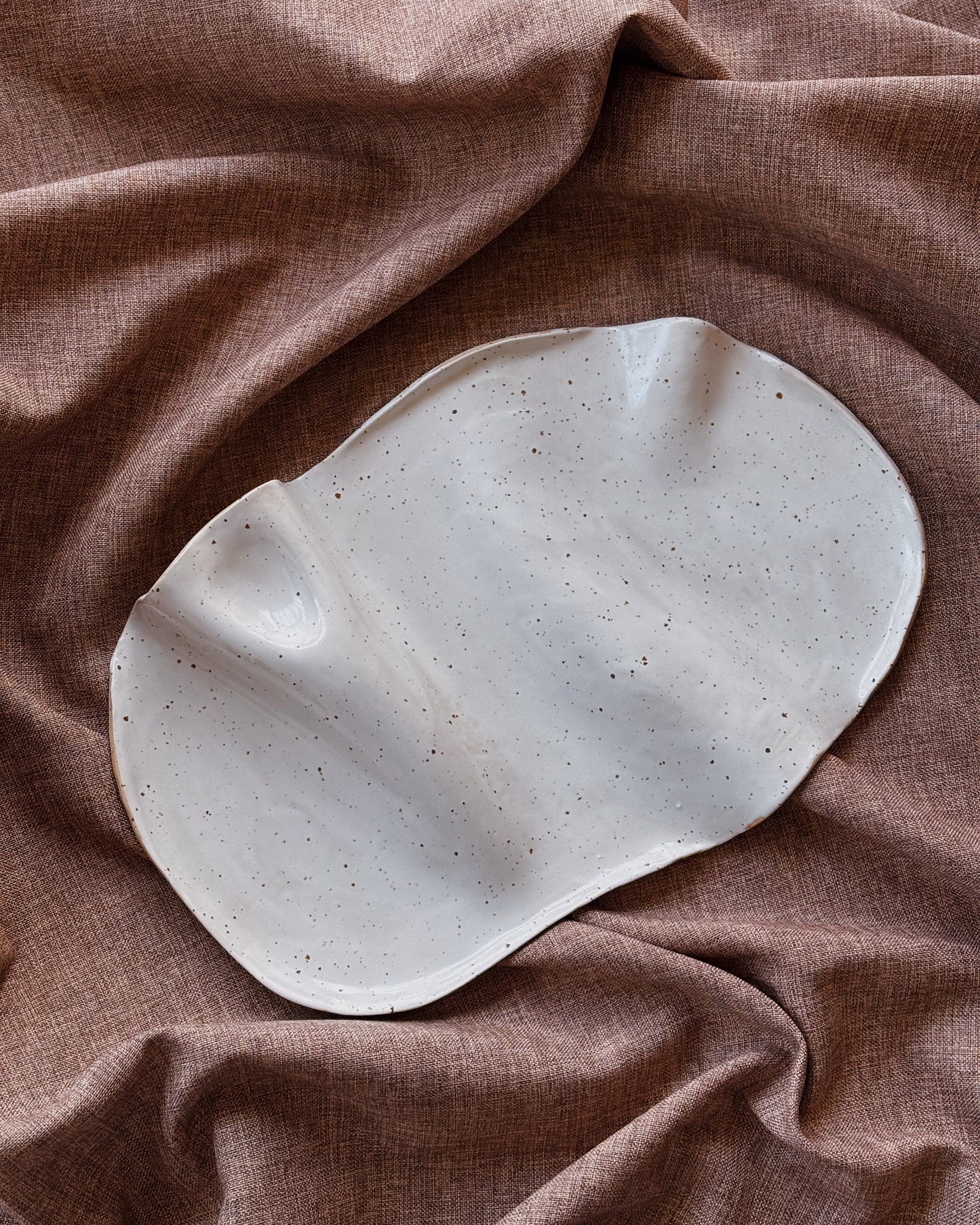 Speckled ceramic plate on a brown fabric background