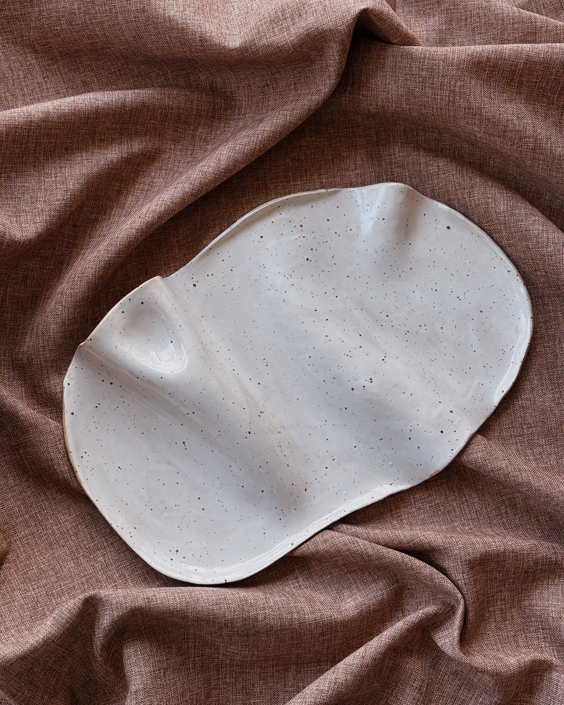 Speckled ceramic plate on a brown fabric background