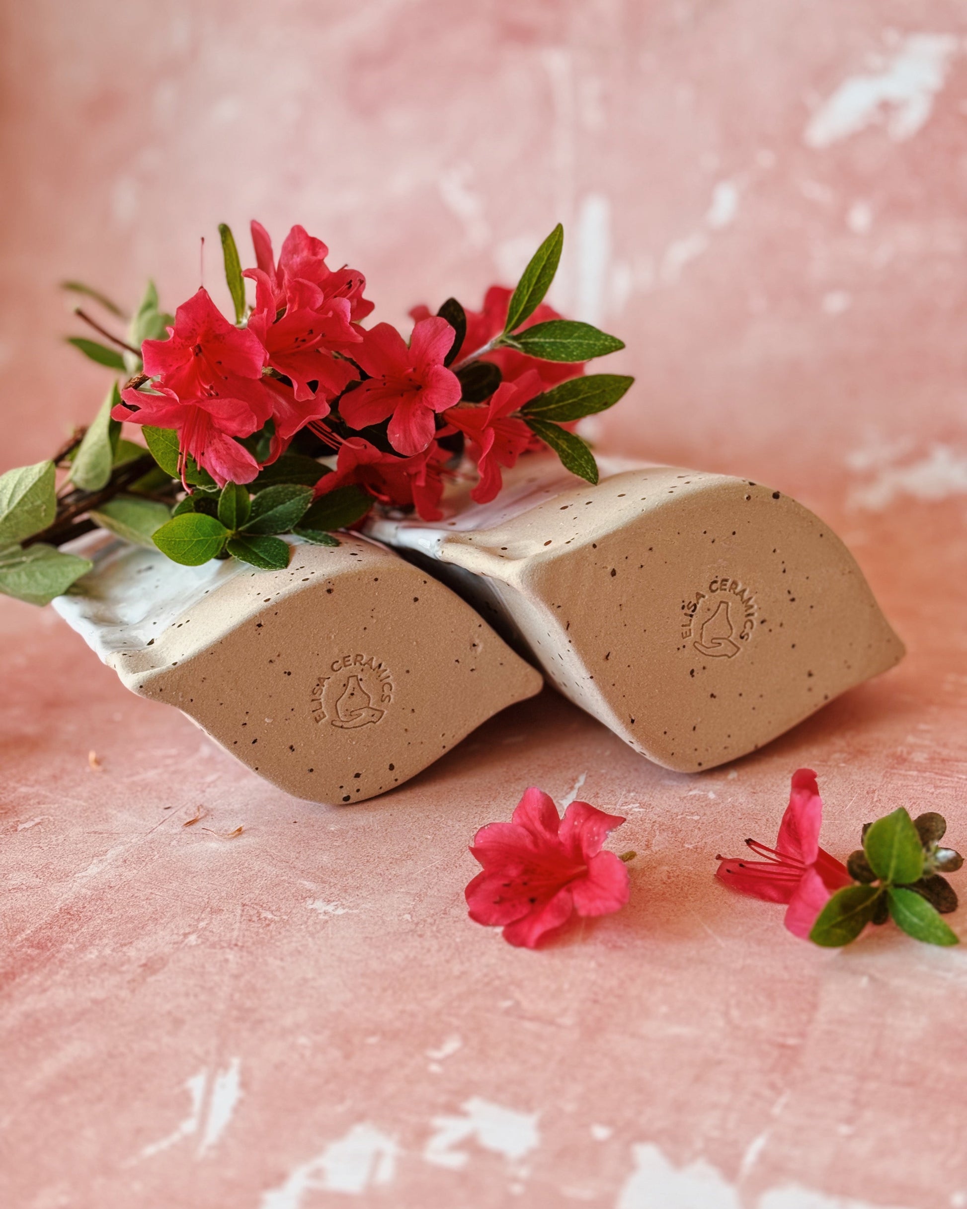 Two beige soap bars with green leaves and pink flowers on a pink textured background