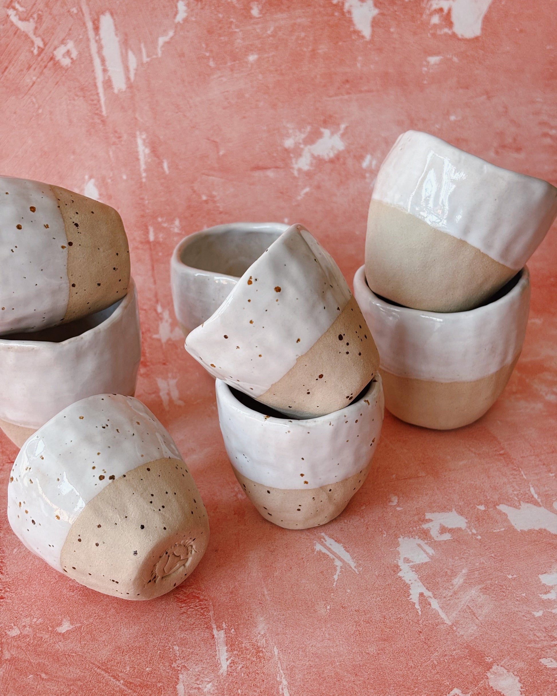 Set of ceramic pots with speckled patterns on a pink surface