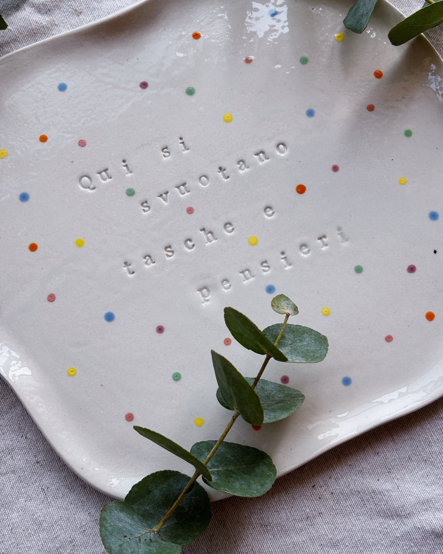 A white handmade ceramic plate featuring some plants