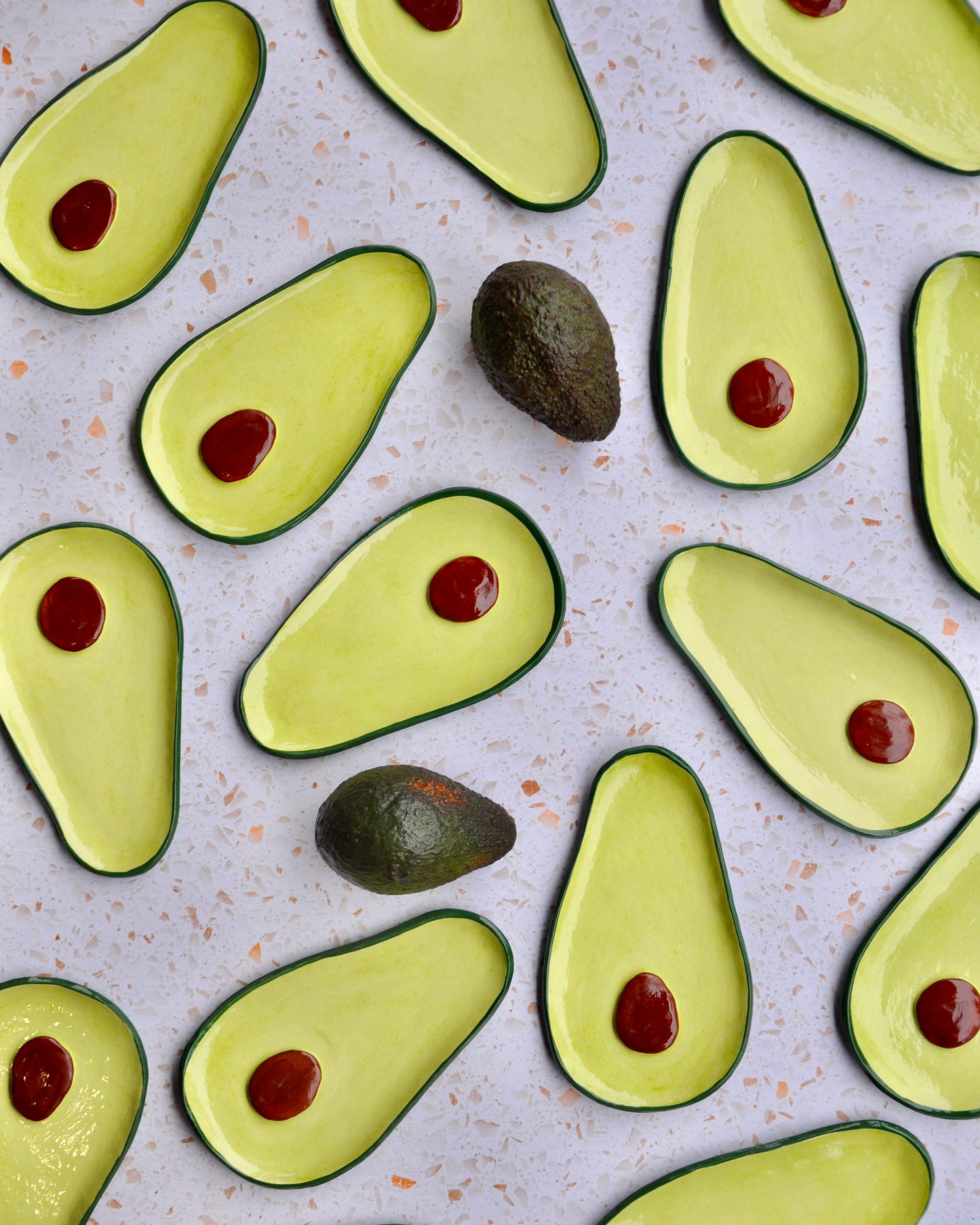 Colorful avocado spoon rest design featuring handmade stoneware with red detailing.