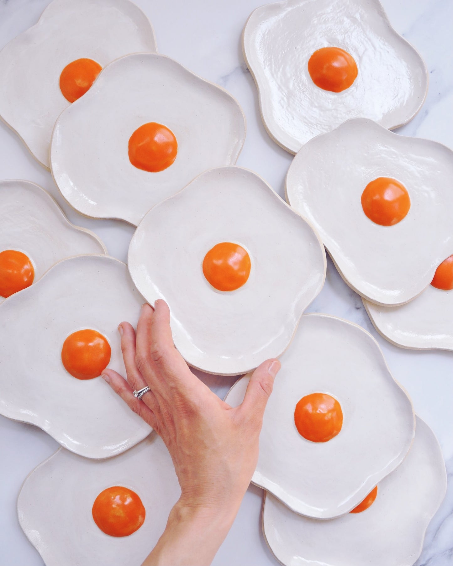 Egg Spoon Rest showcasing handmade stoneware plates with vibrant orange yolks, adding a fun touch to kitchen décor.