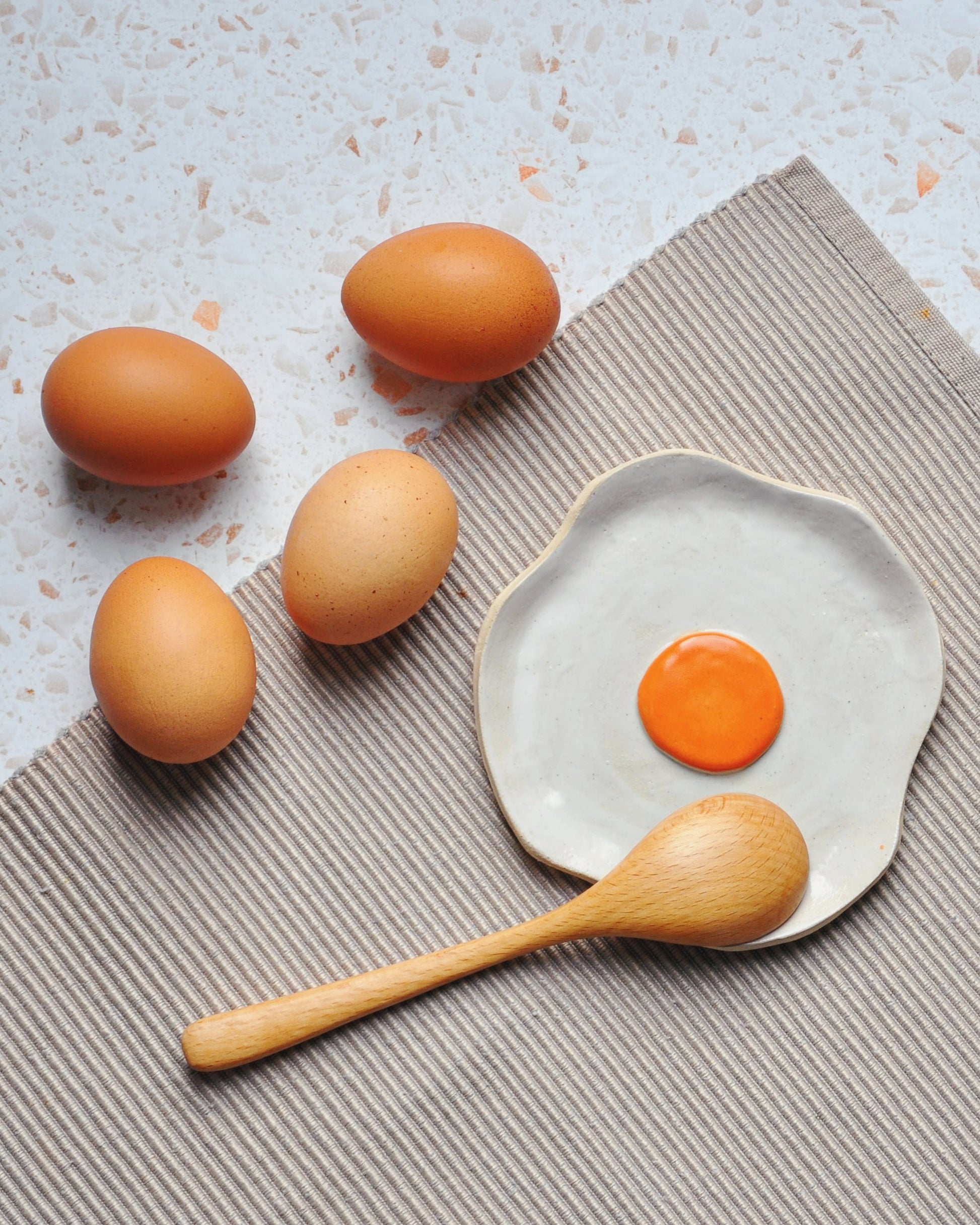Egg Spoon Rest with raw eggs and an egg yolk on a handmade stoneware dish, perfect for a kitchen accent.