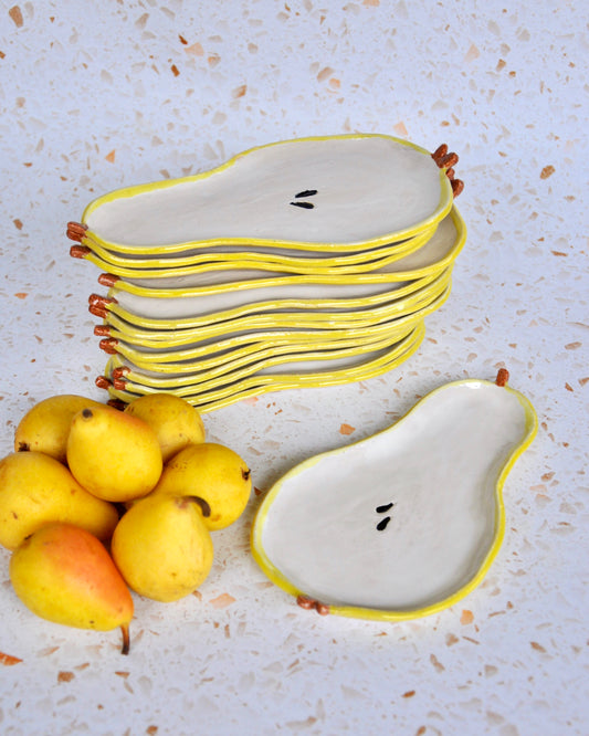 Stack of handmade Pear Spoon Rests with yellow edges next to fresh pears, perfect for decorating your kitchen.