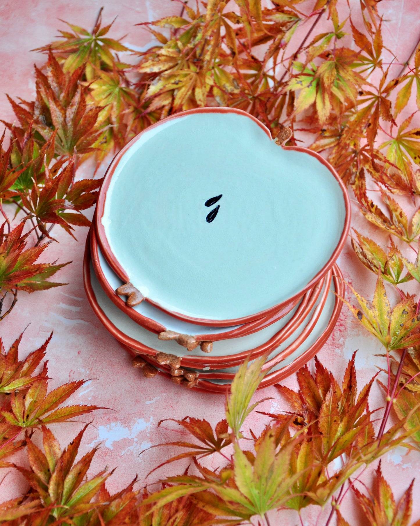 Apple Spoon Rest surrounded by colorful autumn leaves, showcasing its handmade stoneware design.